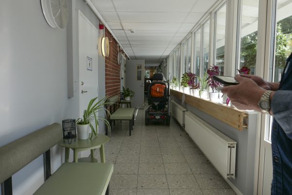 施設内を電動車椅子で移動する高齢者、廊下には椅子が置かれています